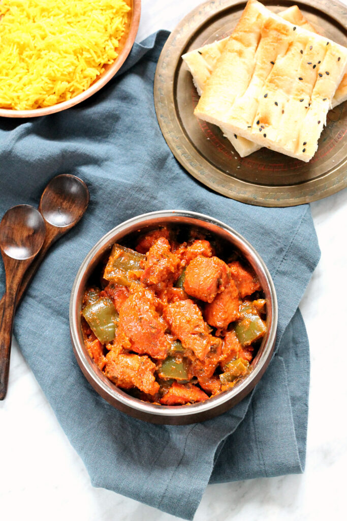 Tandoori Chicken with peppers and onion in a bowl alongside rice and naan.