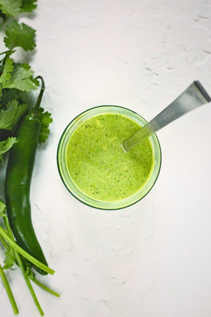 Top view of raita in a jar with a spoon in it.